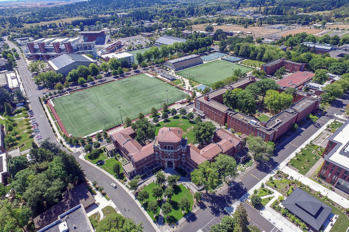 Oregon State University campus walkway lined with brick buildings and tall trees